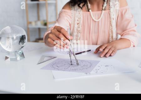 vue rognée de l'astrologue flou dessinant une carte céleste à la maison Banque D'Images