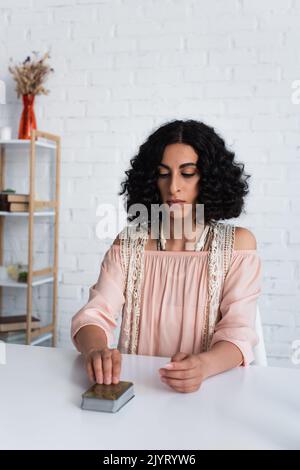 brunette fortune teller assis près du pont de cartes de tarot à la maison Banque D'Images