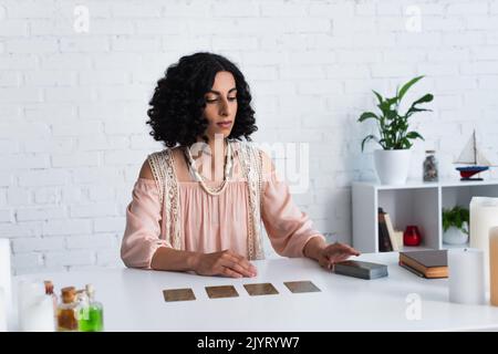 jeune tueur de fortune assis près du pont de cartes de tarot et livre de prédiction Banque D'Images