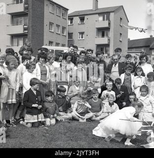 1965, historique, les enfants et les adultes se sont réunis pour une photo de groupe, certains tenant des trophées miniatures, après avoir pris part à la journée de gala du North Queensferry, une journée communautaire pour les résidents du domaine, North Queensferry, Fife, Écosse, Royaume-Uni. Banque D'Images