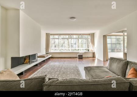 Canapé confortable avec coussins placés contre un mur lumineux avec cheminée électrique et décorations dans le salon moderne Banque D'Images