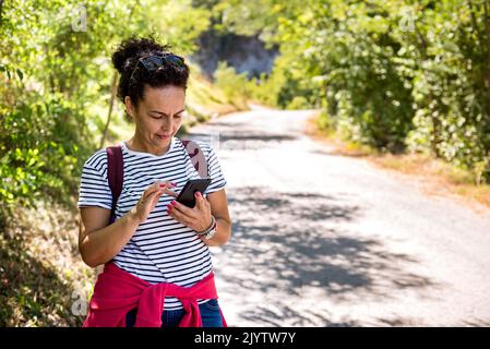 Femme touriste utiliser la navigation sur le smartphone pendant la randonnée le jour ensoleillé d'été. Banque D'Images