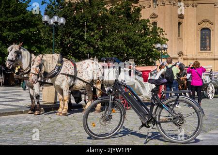 Prague, Tchéquie, 29 août 2022: Vélo électrique noir devant une calèche pour faire du cheval avec les touristes dans le marché de la vieille ville de Prague, Prague et République tchèque Banque D'Images