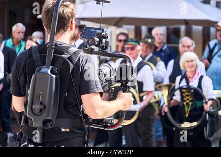 Stolberg, Allemagne, 4 septembre 2022: Cameraman professionnel avec grande nacelle devant le corps filmant le groupe de costumes traditionnels dans les montagnes de Harz Banque D'Images