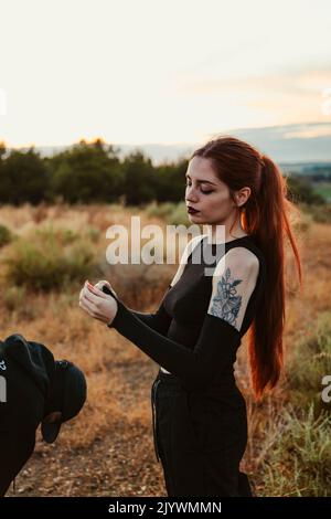 Fille tatouée fumant un joint de marijuana pendant le coucher du soleil Banque D'Images