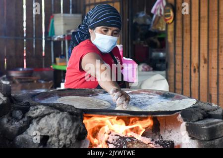 Femme cuisant Tlayudas sur un feu de bois, Oaxaca México Banque D'Images