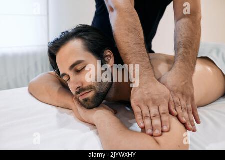 Bel homme bénéficiant d'un massage relaxant lors d'un soin spa dans le centre de bien-être. massothérapie pour client masculin Banque D'Images