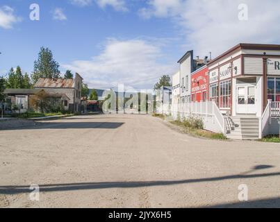 Dawson, territoire du Yukon - 4 août 2008; longues ombres de l'autre côté de la rue poussiéreuse avec des bâtiments des deux côtés. Banque D'Images