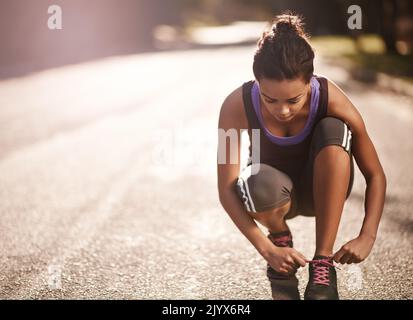 La seule façon de terminer est de commencer : un coureur qui noue ses lacets avant une course. Banque D'Images