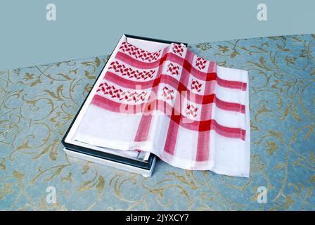 Foulard culturel masculin arabe musulman appelé Shemagh ghutrah isolé rouge et blanc tissu habillement accessoire Moyen-Orient traditionnel Banque D'Images