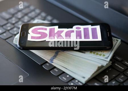 TERNOPIL, UKRAINE - 6 SEPTEMBRE 2022 le logotype de papier Skrill repose sur un clavier noir pour ordinateur portable avec des billets en dollars américains. Payoneer est un service financier américain Banque D'Images