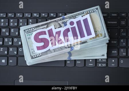 TERNOPIL, UKRAINE - 6 SEPTEMBRE 2022 le logotype de papier Skrill repose sur un clavier noir pour ordinateur portable avec des billets en dollars américains. Payoneer est un service financier américain Banque D'Images