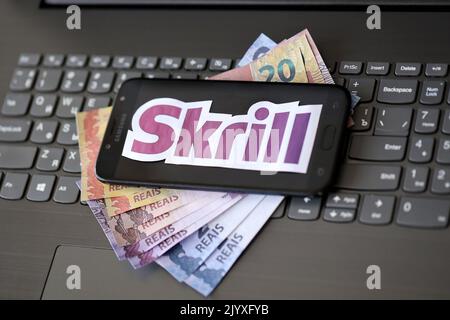 TERNOPIL, UKRAINE - 6 SEPTEMBRE 2022 le logotype de papier Skrill repose sur un clavier noir pour ordinateur portable avec des reals brésiliens. Payoneer est une société financière américaine Banque D'Images