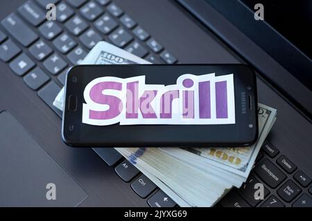 TERNOPIL, UKRAINE - 6 SEPTEMBRE 2022 le logotype de papier Skrill repose sur un clavier noir pour ordinateur portable avec des billets en dollars américains. Payoneer est un service financier américain Banque D'Images