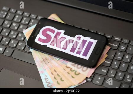 TERNOPIL, UKRAINE - 6 SEPTEMBRE 2022 le logotype de papier Skrill repose sur un clavier noir pour ordinateur portable avec des factures hryvnia ukrainiennes. Payoneer est une société financière américaine Banque D'Images