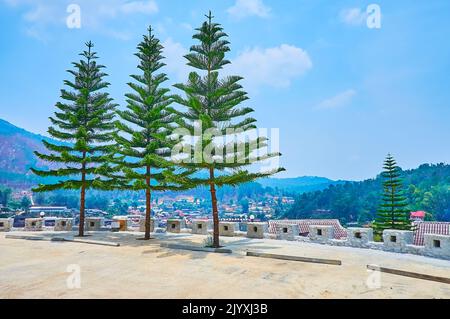 La terrasse d'observation au sommet de la colline dans le village de thé Ban Rak Thai (Mae AW) avec trois grands pins de l'île Norfolk contre le paysage de montagne, la Thaïlande Banque D'Images