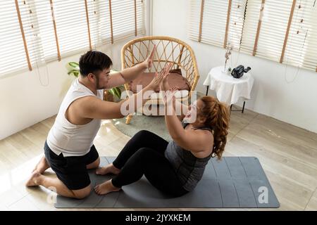 Jeune couple asiatique de chubby s'entraînant et s'entraînant ensemble dans la salle de séjour à la maison. Plus taille homme et femme applaudissent et montrent l'énergie positive et encouragent les uns les autres qu'ils peuvent le faire Banque D'Images