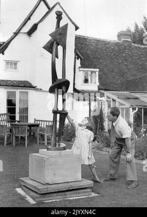 Henry Moore, sculpteur -- Henry Moore dans le jardin de sa maison de campagne - 'Hogland'. En arrière-plan est le cottage de 15th siècle où il vit. Avec le sculpteur est Marie, sa fille de 6 ans. 1 janvier 1952. Banque D'Images