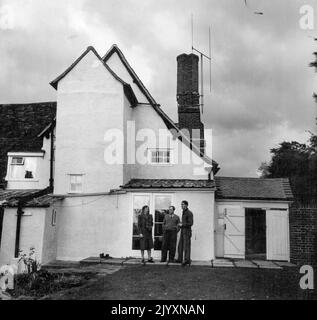 Avec sa femme et Oliffe Richmond, Henry Moore se trouve sur le côté de sa ferme anglaise du XVIe siècle appelée 'Hogland', à Perry Green, à Averyet Hadham (il y a aussi un petit Hadham), un village dans le Hertfordshire. L'antenne de télévision est un peu ce que note incongru sur la cheminée ancienne pile. Les Moores y vivent depuis leur départ de Londres en 1941. 9 octobre 1950. (Photo par (photo par Miller/Fairfax Media). Banque D'Images