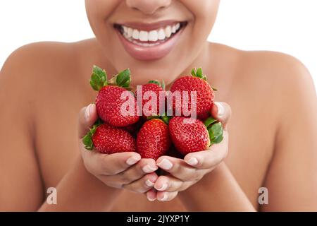 La baie est délicieuse. Photo en studio d'une femme tenant une poignée de fraises. Banque D'Images