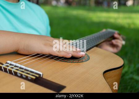 La main du guitariste repose sur les cordes d'une guitare acoustique classique en bois Banque D'Images