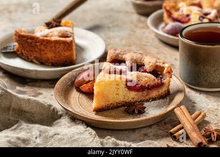 Morceaux de la célèbre tarte Plum Torte ou du New York Times avec épices et thé sur fond texturé style rustique. Orientation de l'horisontal Banque D'Images