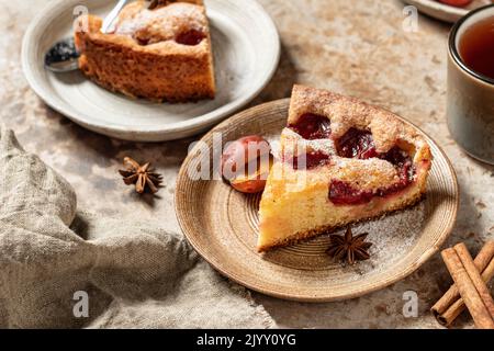 Morceaux de la célèbre tarte Plum Torte ou du New York Times avec épices et thé sur fond texturé style rustique. Orientation de l'horisontal Banque D'Images