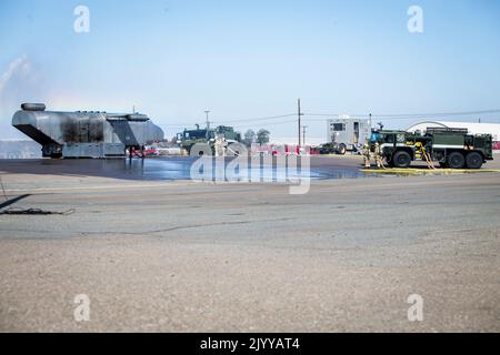 Marines des États-Unis avec sauvetage d'aéronefs et lutte contre les incendies, quartier général et escadron de siège, Marine corps Air Station Miramar, de l'eau pulvérisée sur les flammes provenant d'une unité mobile de combustion lors d'un exercice d'incident d'avion à grande échelle sur MCAS Miramar, San Diego, Californie, le 17 août 2022. Cet exercice d'intervention d'urgence a été effectué pour les premiers intervenants afin de maintenir la compétence et la préparation en cas de menaces et de dangers réels potentiels sur l'installation. (É.-U. Photo du corps marin par lance Cpl. Jose S. GuerreroDeLeon) Banque D'Images