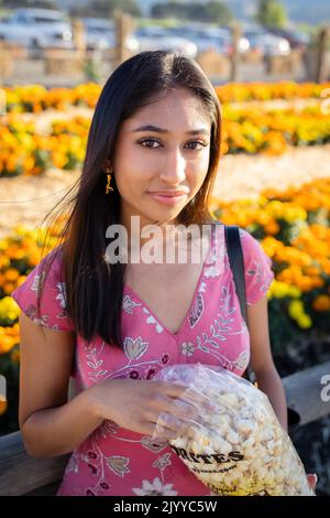 Portrait d'automne de la jeune femme asiatique debout devant un champ de Marigolds orange et jaune | manger Kettle Co Banque D'Images