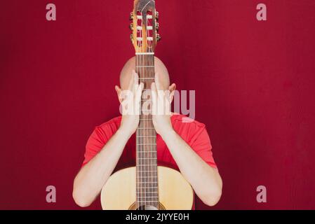 Instrument de musique à cordes. Guitariste masculine charismatique mature. Guy avec barbe tient de la guitare. Homme barbu dans une chemise rouge. Interprète musical de la musique. Banque D'Images