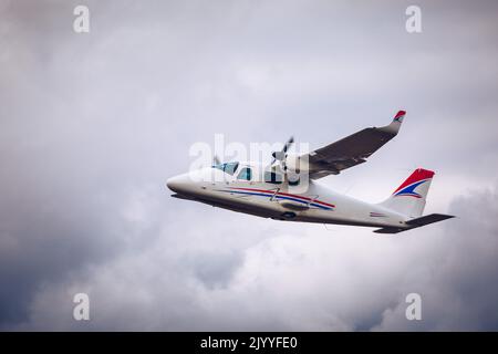 Léger petit avion vole contre le fond de nuages pluvieux blancs pas haut au-dessus du sol. Avion léger en plein air. Un petit avion touristique sur un Banque D'Images