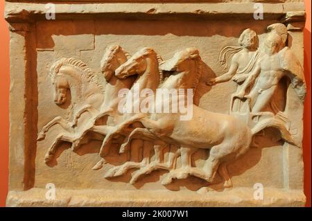Un relief grec antique en pierre ruinée dépeignant des hommes sur un char Banque D'Images