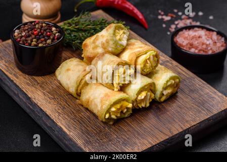 Rouleaux d'entrée de courgettes avec fromage à la crème et œufs sur une planche à découper sur fond gris foncé Banque D'Images