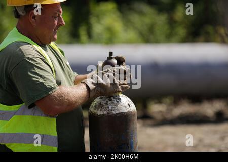 Bucarest, Roumanie - 8 septembre 2022: Faible profondeur de champ (foyer sélectif) détails avec un travailleur manipulant un réservoir d'oxygène industriel. Banque D'Images