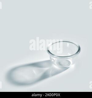 bol en verre vide avec une longue ombre sur fond blanc Banque D'Images