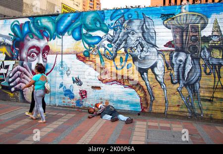 Colombie, Medellin, homme sans abri est en train de poser devant une copie de peinture murale de Dali. Banque D'Images