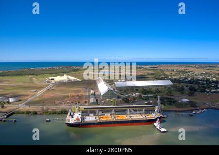 Vue aérienne d'un cargo en cours de chargement dans un terminal par la côte avec un ciel bleu profond au-dessus de Port Bundaberg Qld Australie Banque D'Images