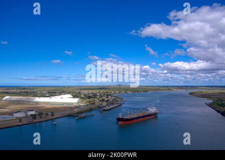 Vue aérienne d'un cargo dans une rivière près de bâtiments industriels sous un ciel bleu nuageux Port Bundaberg, Queensland, Australie Banque D'Images