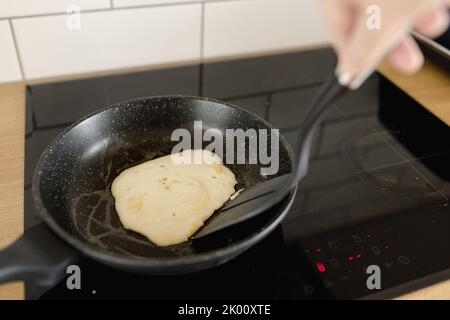 retourner une crêpe partiellement cuite dans une poêle Banque D'Images