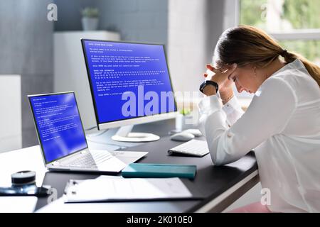 Femme inquiète à l'ordinateur avec écran de défaillance du système sur le lieu de travail Banque D'Images