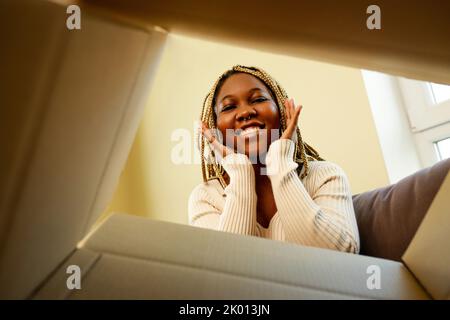 bonne femme afro-américaine regardant à l'intérieur de la boîte et surpris de mignon animal de compagnie Banque D'Images