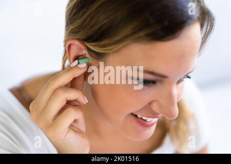 Femme utilisant des bouchons d'oreilles dans la chambre d'accueil Banque D'Images