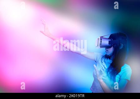 Femme portant 3D lunettes immergées dans la fantaisie virtuelle du monde de rêve de verset méta sous le faisceau de lumière. Banque D'Images