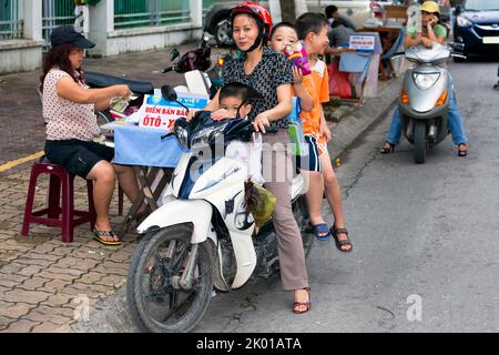 Mère vietnamienne et enfants sur moto acheter à la rue vendeur, Hai Phong, Vietnam Banque D'Images