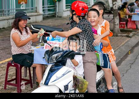 Mère vietnamienne et enfants sur moto acheter à la rue vendeur, Hai Phong, Vietnam Banque D'Images