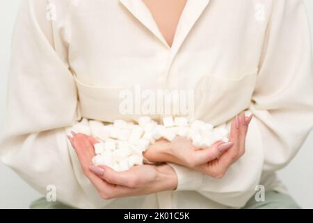 Portrait d'une jeune femme caucasienne tenant des cubes de sucre en tas debout et regardant l'appareil photo sur un fond blanc Banque D'Images