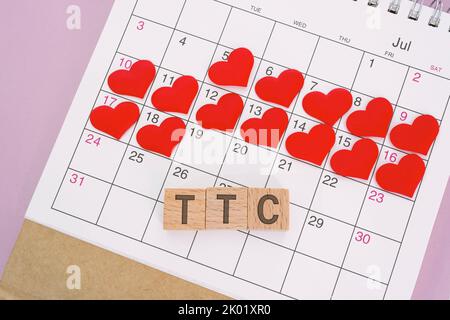 Mot TCC sur bloc de bois avec coeur rouge sur le calendrier. Survivre les deux semaines attendez quand vous essayez de concevoir. Banque D'Images