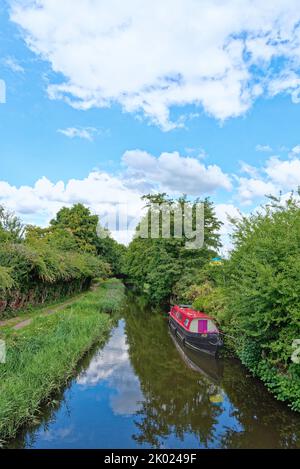 Un bateau étroit avec une superstructure rouge amarré sur le canal de navigation de la rivière Wey dans la campagne près de Ripley Surrey Angleterre Banque D'Images