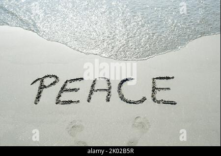 Concept ou conceptuel texte de paix manuscrit dans le sable sur une plage avec des vagues dans une île exotique pour tropical, été, mer, océan, calendrier, voyages, ho Banque D'Images
