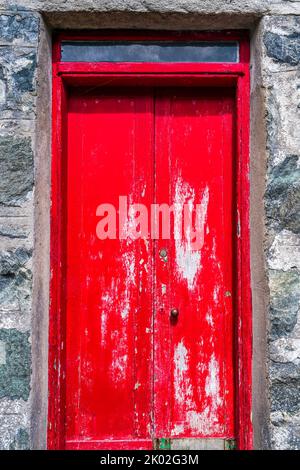 Porte en bois rouge abîmé dans le vieux bâtiment en pierre Banque D'Images